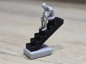 Escultura hombre pensativo en escaleras